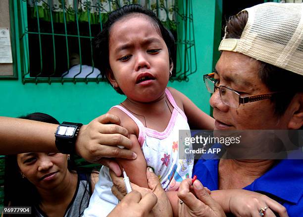 Filipino nurse injects a girl with a measles vaccine in a slum area in Tondo, Manila, on February 23, 2010. The Department of Health has declared an...