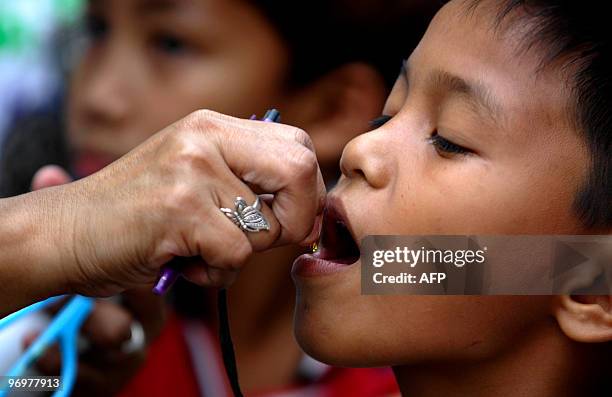 Filipino nurse gives a boy vitamins after recieving a measles vaccine injection in a slum area in Tondo, Manila, on February 23, 2010. The Department...