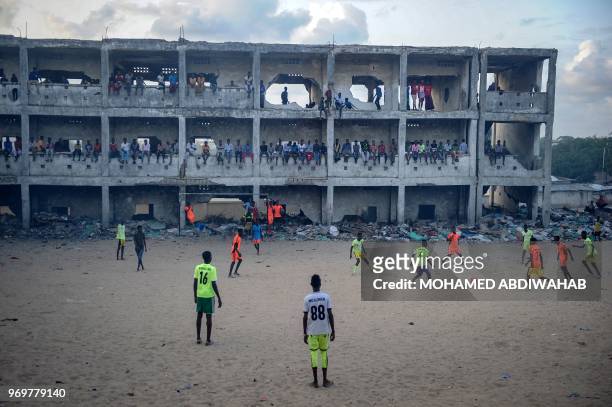Somali people play football in the smoky air due to burning litters at the destroyed and abandoned secondary school since 1991, in Mogadishu,...