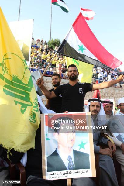 Lebanese Shiite Muslims carry a portrait of Syrian president Bachar al-Assad, a Syrian national flag as well as a flag of the Shiite Hezbollah...