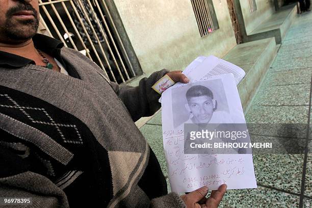Pakistani man, Asghar Ali displays a portrait of his missing nephew Muhammed Bagher as he searches for him at a rehabilitation center for homeless...