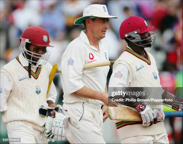 Ashley Giles of England leaves the field with West Indies' batsmen Shivnarine Chanderpaul and Fidel Edwards at the end of the 1st Test match between...