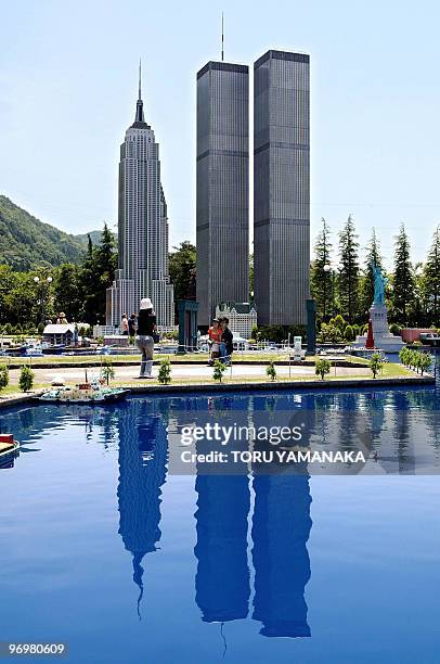 The 20-meter-high replicas of the World Trade Center and the Empire State Building are reflected on a pond at the Tobu World Square theme park, which...