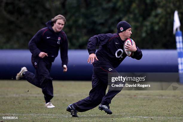 Jonny Wilkinson runs with the ball as Mathew Tait looks on during the England training session held at Pennyhill Park on February 23, 2010 in...