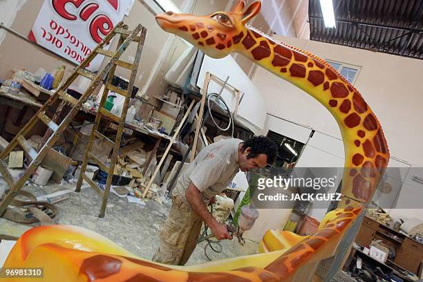 An artist works on a model giraffe for a parade float in Kalmaniya, near Kfar Saba, on February 23, 2010 in preparation for the Jewish holiday of...
