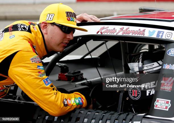 Kyle Busch, driver of the M&M's Red White & Blue Toyota, talks to Kevin Harvick, driver of the Jimmy John's Ford, on the grid during qualifying for...