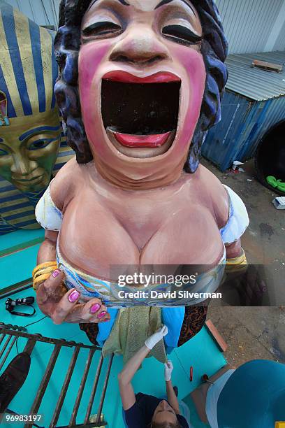 Woman tacks a dress to an oversized opera singer as workers put the final touches on dozens of large colourful floats to be used next week in Purim...