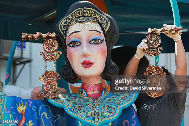 Man attaches decorations to an oversized dancer as workers put the final touches on dozens of colourful floats to be used next week in Purim...