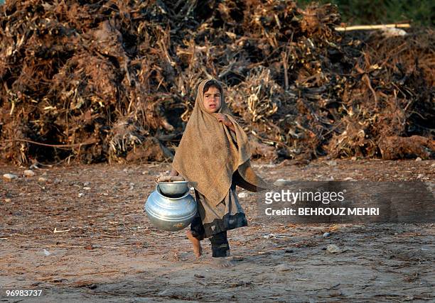 Pakistani ethnic Pashtun girl takes a milk jar outside her makeshift house in the town of Khewra some 200 kms south of the capital Islamabad on...