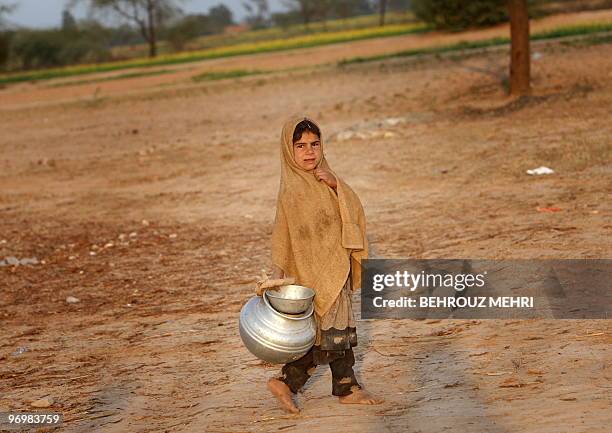 Pakistani ethnic Pashtun girl takes a milk jar outside her makeshift house in the town of Khewra some 200 kms south of the capital Islamabad on...