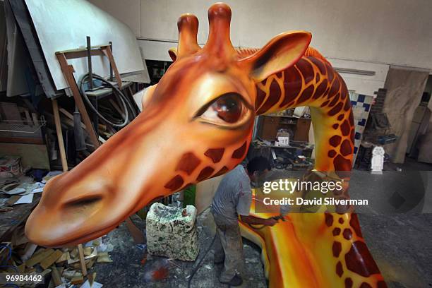 Worker paints the model of a giraffe to be added to one of dozens of large colourful floats for use in next week's Purim carnivals throughout the...