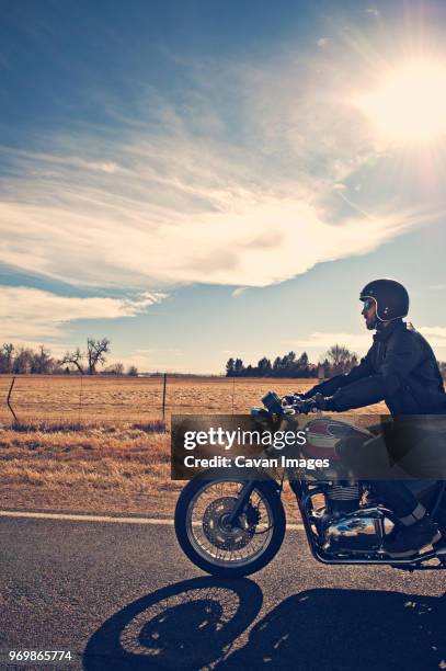 biker riding against cloudy sky - motorcycle travel stock-fotos und bilder