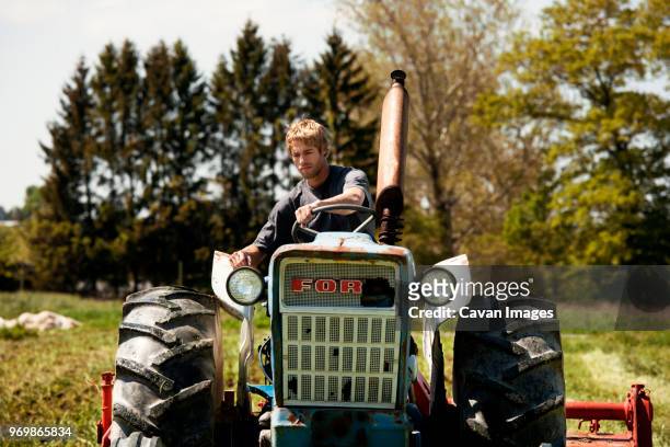 farmer pulling harrow with tractor on field - cavan images stock-fotos und bilder