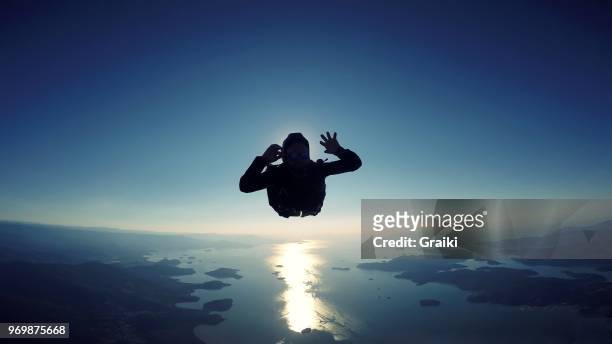skydiving man jumping over the sea at a sunrise - tomber en chute libre photos et images de collection