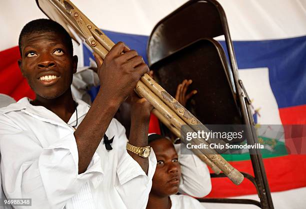 Haitian Voodooists cover their heads with metal chairs after their ceremony for earthquake victims came under attack from Christian residents of the...