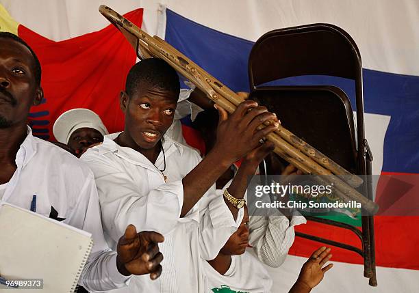 Haitian Voodooists cover their heads with metal chairs after their ceremony for earthquake victims came under attack from Christian residents of the...