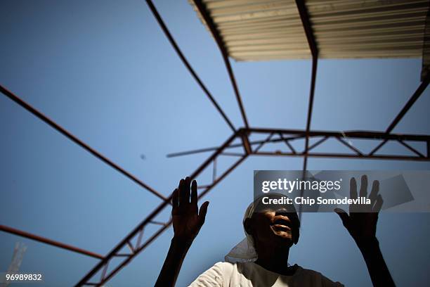 Just paces away from where a Christian mob attacked a Haitian Voodoo ceremony for earthquake victims, an old woman prays in an earthquake-damaged...