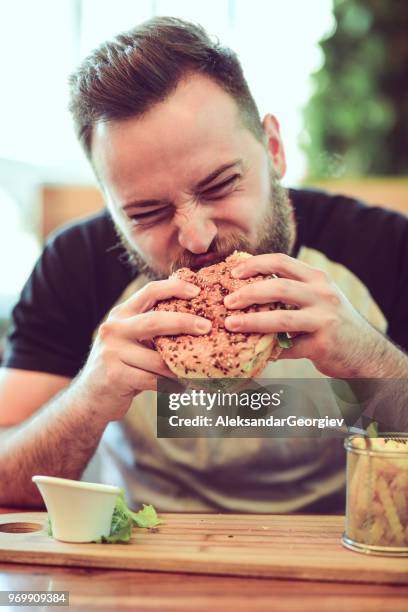 macho comiendo una hamburguesa en restaurante de comida rápida - male burger eating fotografías e imágenes de stock