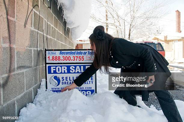 Realtor Sarah Carmona of Sellstate Dreams Realty moves snow in front of a "For Sale" sign outside a foreclosed home in Reno, Nevada, U.S., on Monday,...