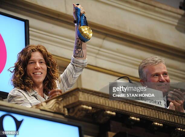 Olympic snowboard gold medalist Shaun White holds his gold medal aloft beside Duncan L. Niederauer , President of the New York Stock...