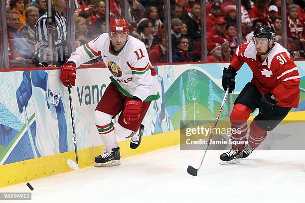 Aleksandr Kulakov of Belarus and Mathias Seger of Switzerland chase the puck during the ice hockey Men's Qualification Playoff game between...