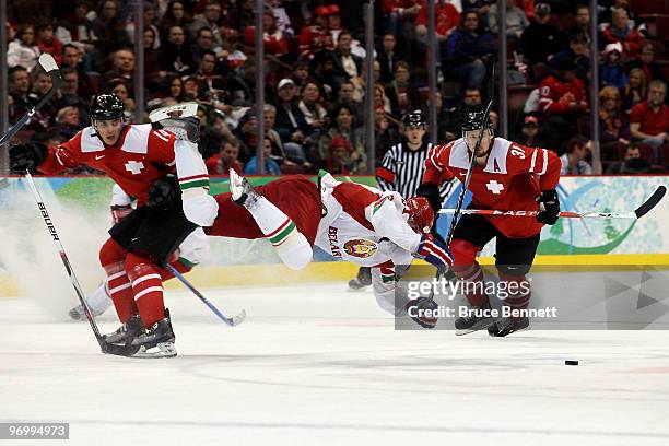 Roman Wick of Switzerland trips Konstantin Zakharov of Belarus in overtime during the ice hockey Men's Qualification Playoff game between Switzerland...