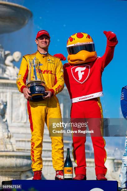 Ryan Hunter-Reay, driver of the Honda Indy Car for Andretti Autosport and the Firestone Tire mascot "FireHawk" pose for pictures with his first place...