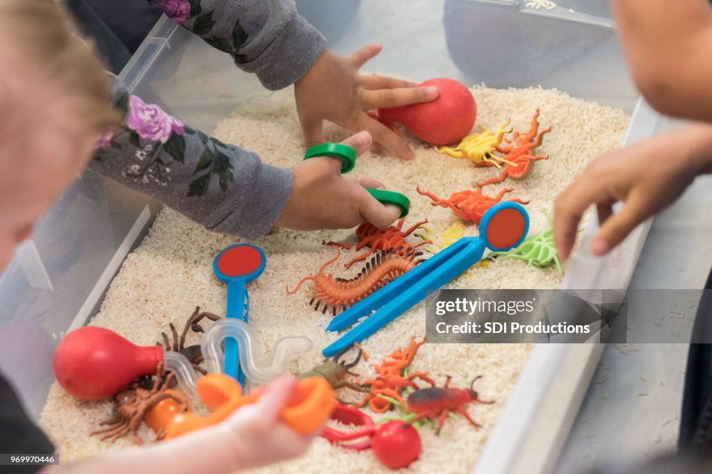 Unrecognizable children play in sensory bin