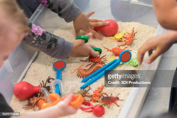 unrecognizable children play in sensory bin - sensory perception stock pictures, royalty-free photos & images