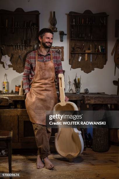 Polish musician and instrument-maker Mateusz Raszewski poses with a kalisz bass that he is building on May 10, 2018 at his workshop in the village of...