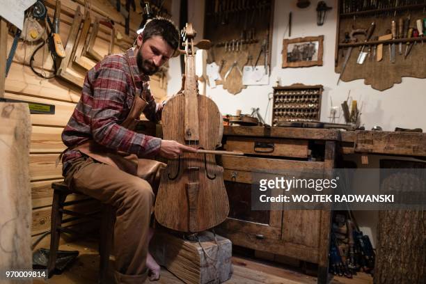 Polish musician and instrument-maker Mateusz Raszewski works on a kalisz bass at his workshop on May 10, 2018 in the village of Kamiensko, just north...
