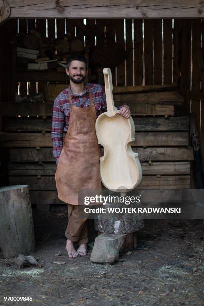 Polish musician and instrument-maker Mateusz Raszewski poses with a kalisz bass that he is building on May 10, 2018 at his workshop in the village of...