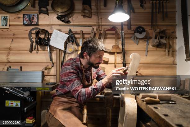 Polish musician and instrument-maker Mateusz Raszewski shapes a kalisz bass at his workshop on May 10, 2018 in the village of Kamiensko, just north...