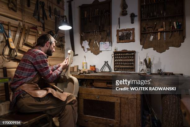 Polish musician and instrument-maker Mateusz Raszewski works on a kalisz bass at his workshop on May 10, 2018 in the village of Kamiensko, just north...