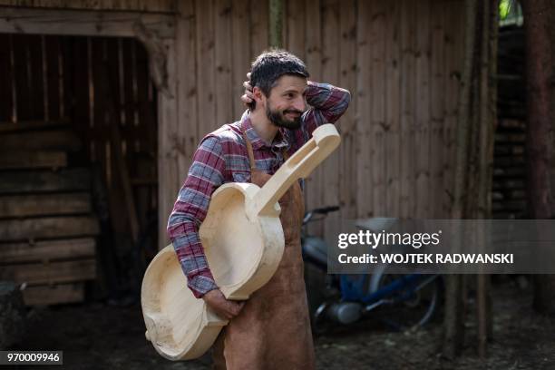 Polish musician and instrument-maker Mateusz Raszewski poses with a kalisz bass that he is building on May 10, 2018 at his workshop in the village of...