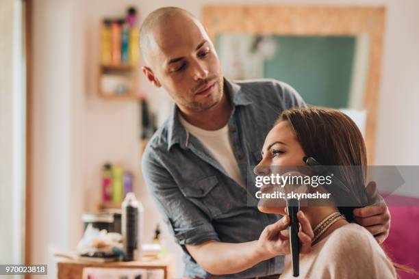 male make-up artist applying blush on young woman's cheek. - maquilhador imagens e fotografias de stock