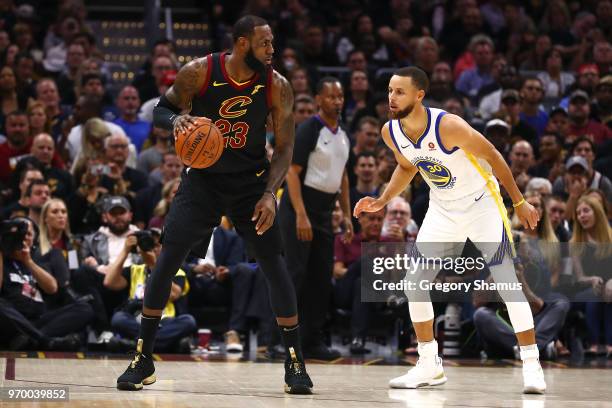 LeBron James of the Cleveland Cavaliers dribbles with the ball defended by Stephen Curry of the Golden State Warriors during Game Four of the 2018...