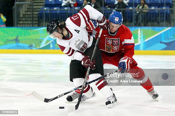 Aleksandrs Nizivijs of Latvia is tackled by Marek Zidlicky of Czech Republic during the ice hockey Men's Play-off qualification match between the...