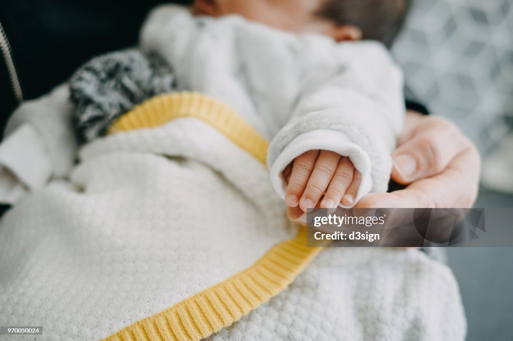 Cropped image of caring grandmother holding the hand of new born baby at home