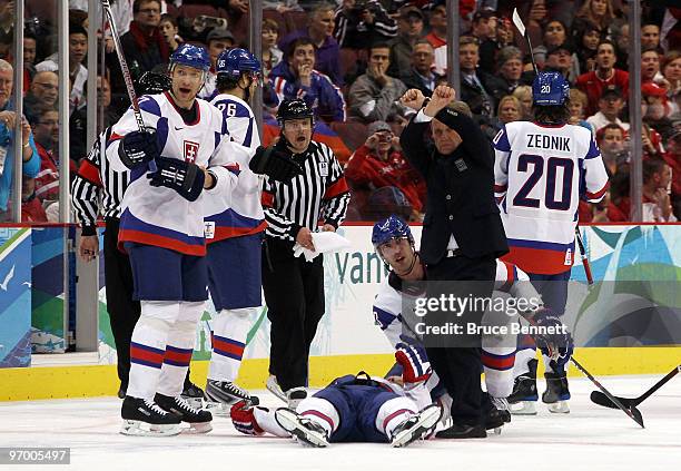 An official and Lubomir Visnovsky of Slovakia reacts towards the bench as Lubos Bartecko of Slovakia lies motionless on the ice in the first period...