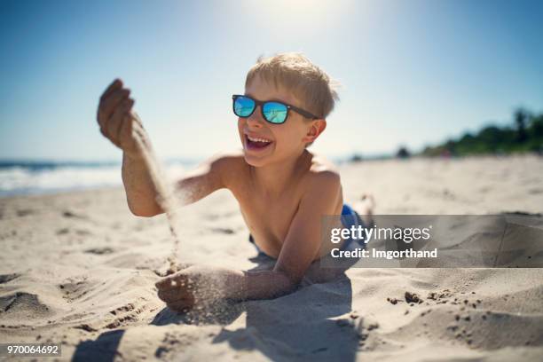 kleine jongen spelen met zand op het strand - alleen jongens stockfoto's en -beelden