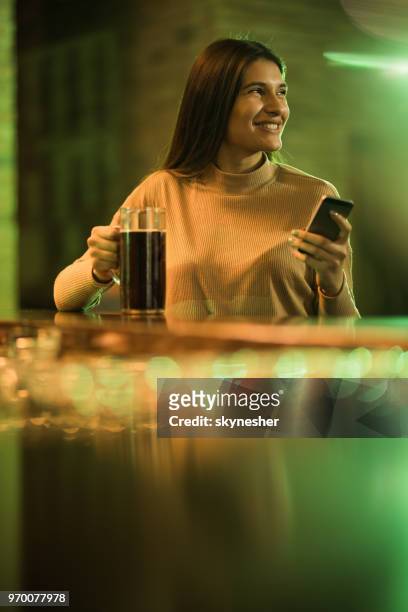 gelukkige vrouw met behulp van mobiele telefoon terwijl het drinken van bier in een pub. - happy mobile stockfoto's en -beelden