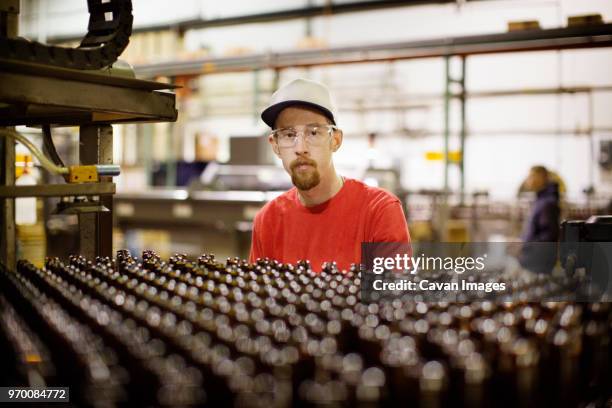 portrait of worker working at beer manufacturing industry - bierflaschen fließband stock-fotos und bilder