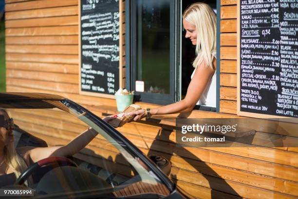 drive-in caffe female clerk with sandwich - drive thru restaurant stock pictures, royalty-free photos & images