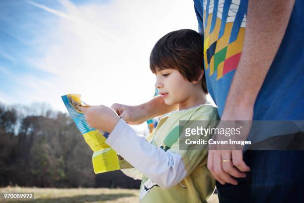 cropped image of boy assisting brother in reading pamphlet - pamphlet stock pictures, royalty-free photos & images