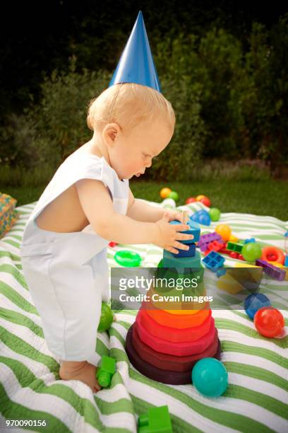 side view of baby boy plying on picnic blanket in lawn - plying stock pictures, royalty-free photos & images