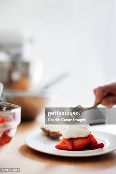 cropped image of hand adding cream to strawberries - strawberry and cream stock pictures, royalty-free photos & images