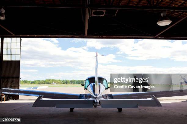 mechanics standing at airplane hangar against cloudy sky - propeller airplane stock pictures, royalty-free photos & images