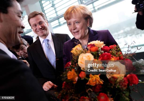 German Chancellor Angela Merkel holds flowers as she congratulates Health Minister Philipp Roesler on his birthday as Vice Chancellor and Foreign...