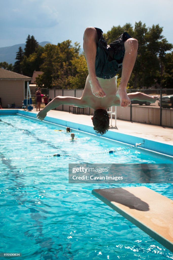 Rear view of teenage boy jumping in swimming pool